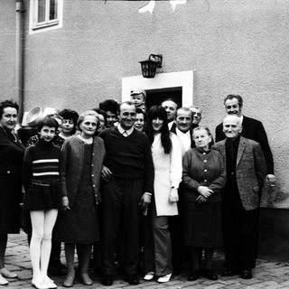 Group of people posing together outdoors in 1960s attire.
