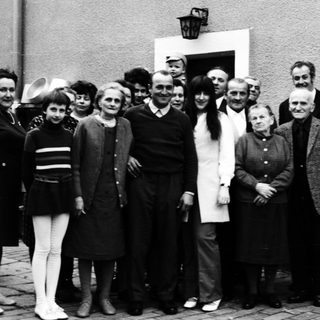 Group of people posing together outdoors in 1960s attire.