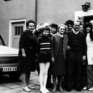 Group of people posing together outdoors in 1960s attire.