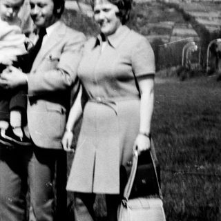 Family group photo with baby outdoors in 1970s.