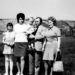 Family group photo with baby outdoors in 1970s.