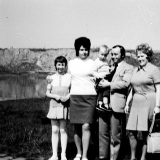 Family group photo with baby outdoors in 1970s.