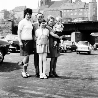 Family posing near historic cathedral with vintage cars.