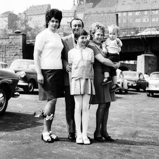 Family posing near historic cathedral with vintage cars.