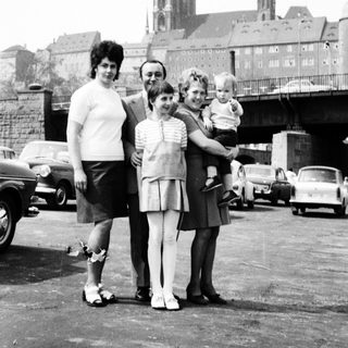 Family posing near historic cathedral with vintage cars.