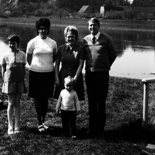 Family posing outdoors near a lake.