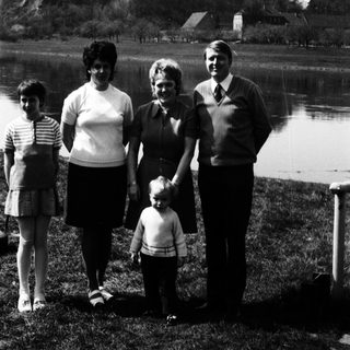 Family posing outdoors near a lake.