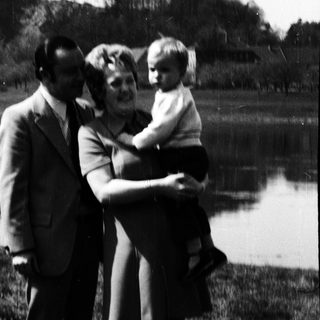 Family posing by a lake with mountainous background.