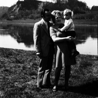 Family posing by a lake with mountainous background.