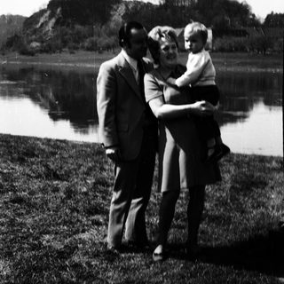 Family posing by a lake with mountainous background.