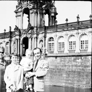 Family posing outside historic palace façade.
