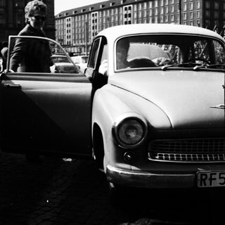 Classic car with open door in urban street scene.