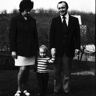 Family portrait with mother, father, and child outdoors.