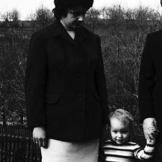 Family portrait with mother, father, and child outdoors.