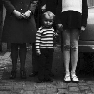 Family portrait outside residential house in 1950s.