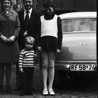 Family portrait outside residential house in 1950s.