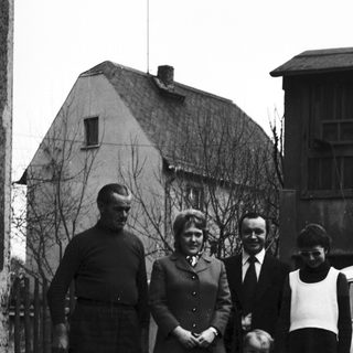 Family portrait outside residential house in 1950s.