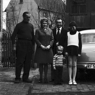 Family portrait outside residential house in 1950s.
