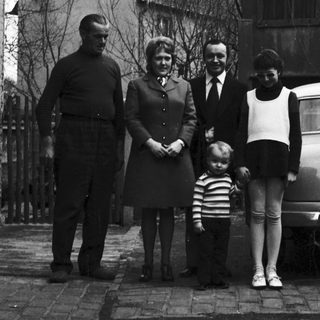 Family portrait outside residential house in 1950s.