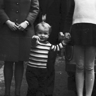 Family portrait with four adults and a child in front of a car, 1960s.