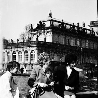 Three women sitting near grand palace.