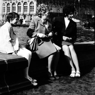 Three women sitting near grand palace.