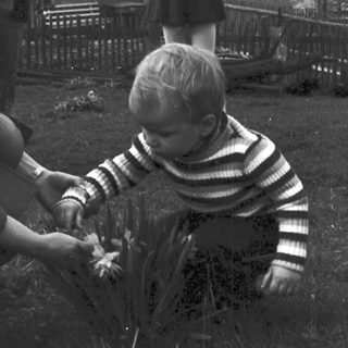 A woman helps a young child plant something outdoors.