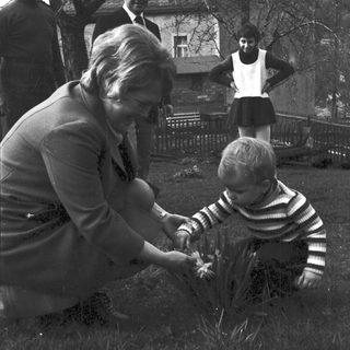 A woman helps a young child plant something outdoors.