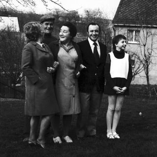Five people posing outdoors in 1960s-style clothing.