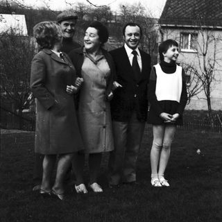 Five people posing outdoors in 1960s-style clothing.