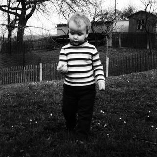 Young child playing outdoors in grassy yard.