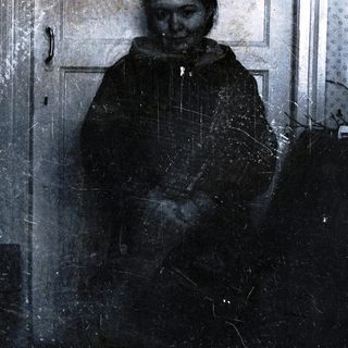 Person standing in doorway with snow-covered coat.