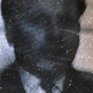 Blurred reflection of man in dark suit.