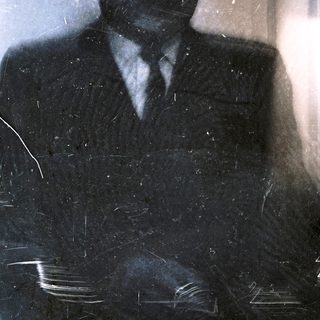 Blurred reflection of man in dark suit.