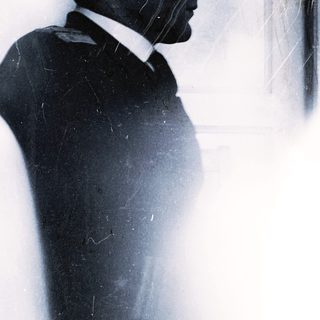 Silhouette of man in suit against frosted glass.