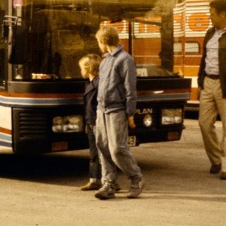 Two tour buses with passengers boarding.