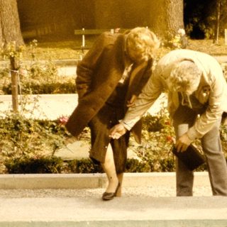 Two people tending pond plants in garden.