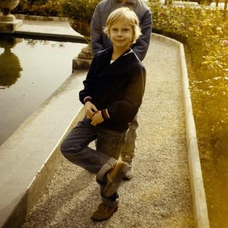 Two boys posing on concrete steps near water fountain.