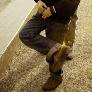 Two boys posing on concrete steps near water fountain.