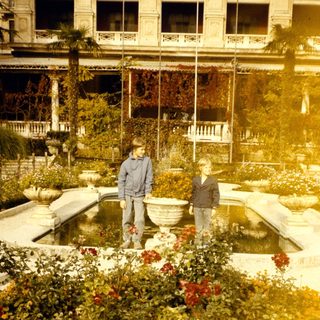 Two people standing by a fountain in a historic garden.