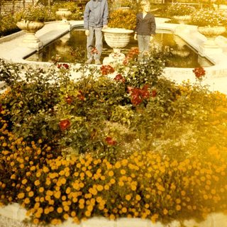 Two people standing by a fountain in a historic garden.