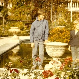 Two people standing by a fountain in a historic garden.
