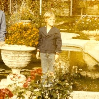 Two people standing by a fountain in a historic garden.