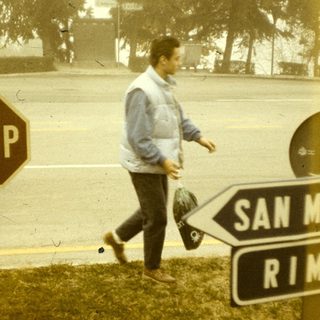 Man walking past stop sign near San Marino and Rimini road signs.