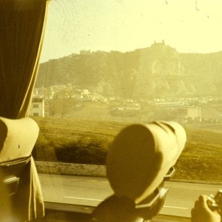 Two people viewing castle ruins from a moving vehicle.