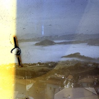 Coastal town with lake and hills.