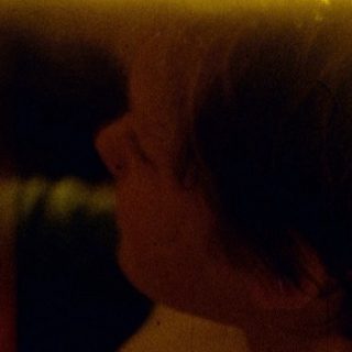 Person sitting alone in dimly lit room.