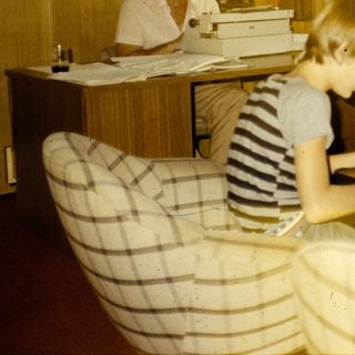 Office setting with woman typing, two children working at desk.