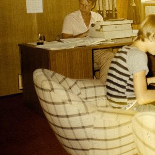 Office setting with woman typing, two children working at desk.