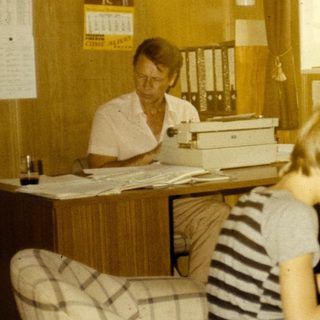 Office setting with woman typing, two children working at desk.